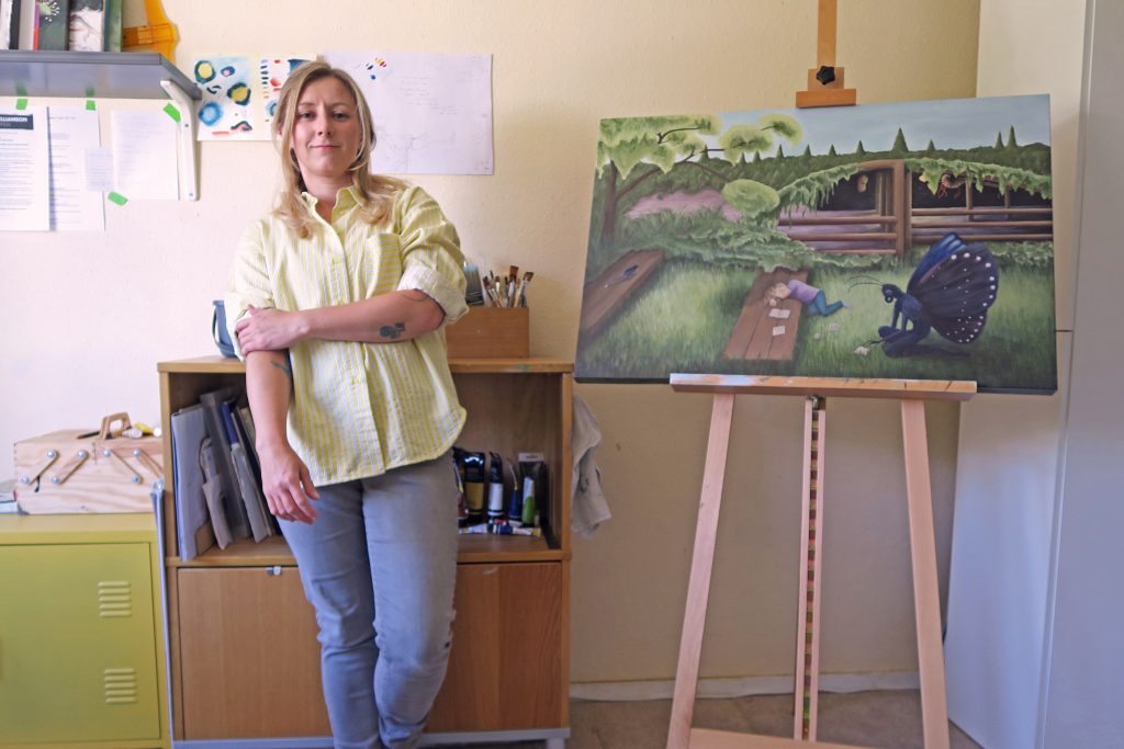 Laura Caseberry standing in home studio next to the painting titled 'Idea' April 2026.